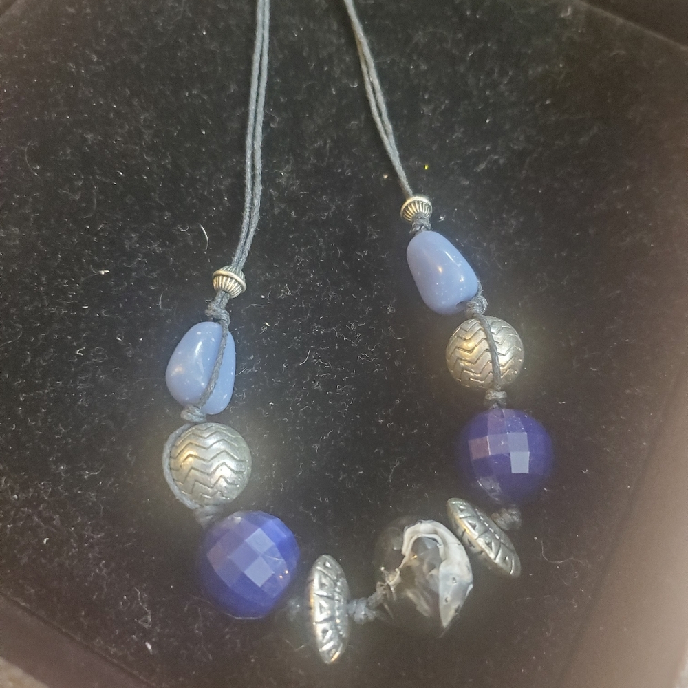Black thread necklace with blue and silver beads.